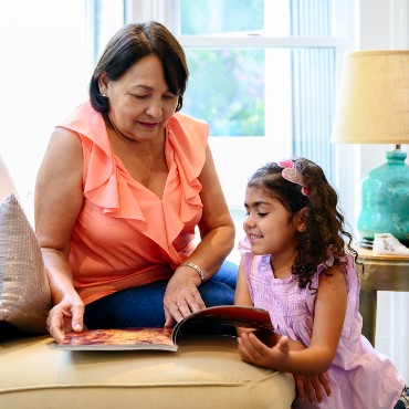 Grandmother reads to her granddaughter on the couch