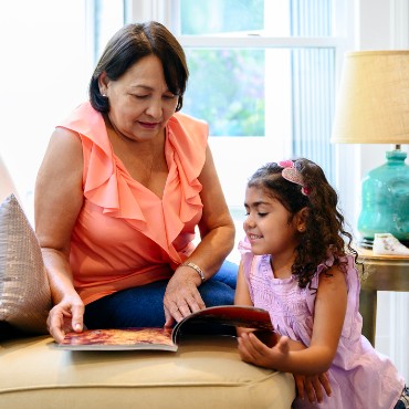 abuela leyendo a su nieta en el sofá