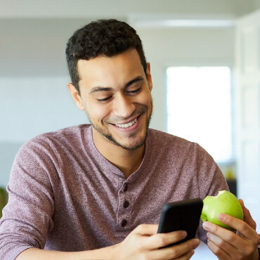 young man smiling while looking at health plans on his phone