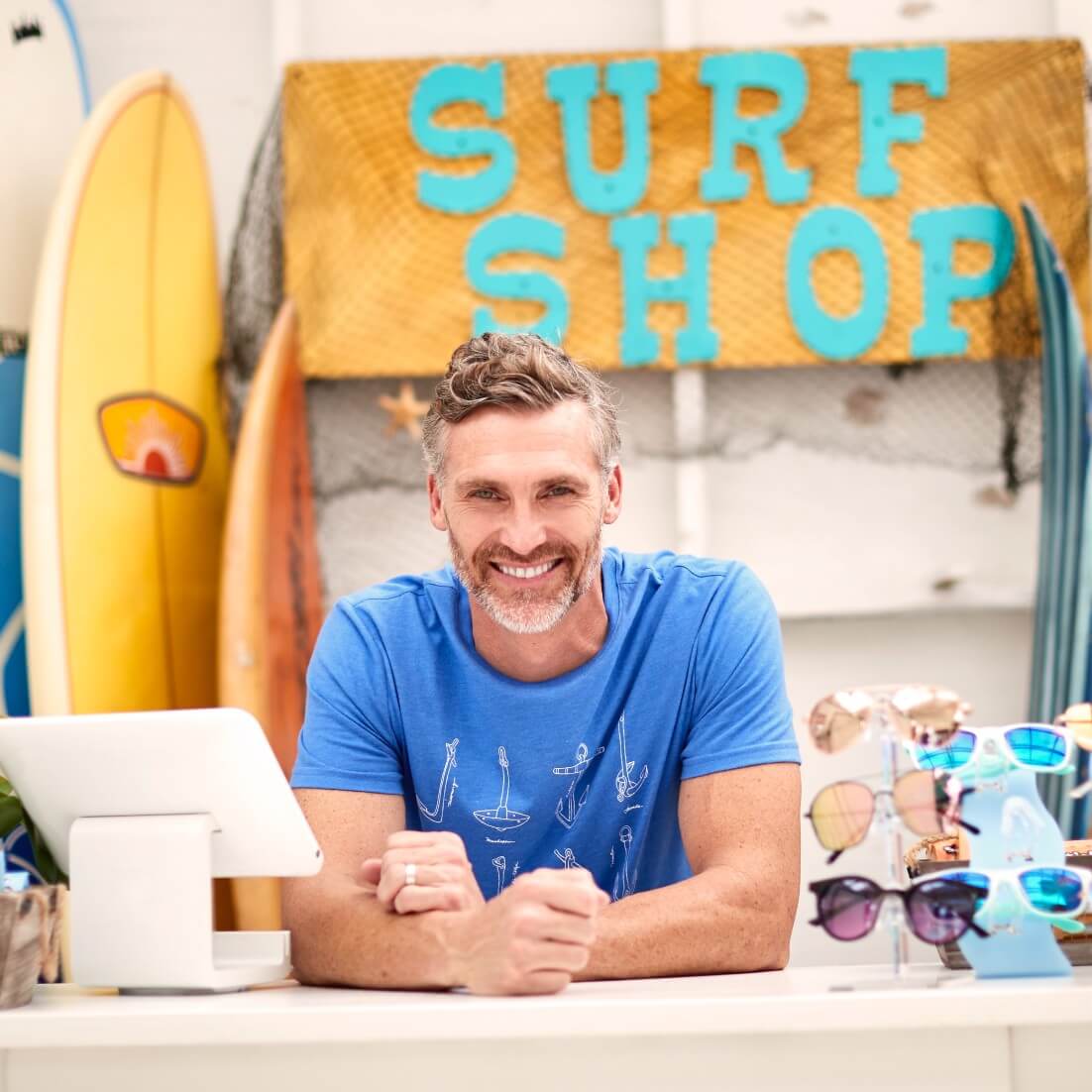 small surfing store owner at front desk smiling