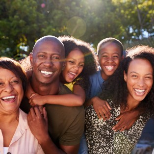 retrato al aire libre de una familia de varias generaciones en el jardín de su casa contra el sol brillante