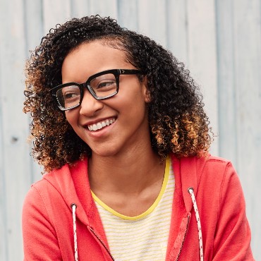 Young person smiling and wearing glasses