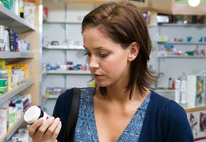 Woman at pharmacy looking at pill bottle